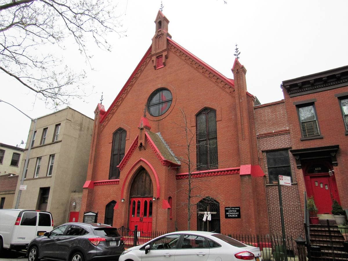 A red-brick Gothic church and brownstones on a Brooklyn street