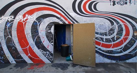 Close view of black, red and white curving bands painted round an open doorway, covered in handwritten notes