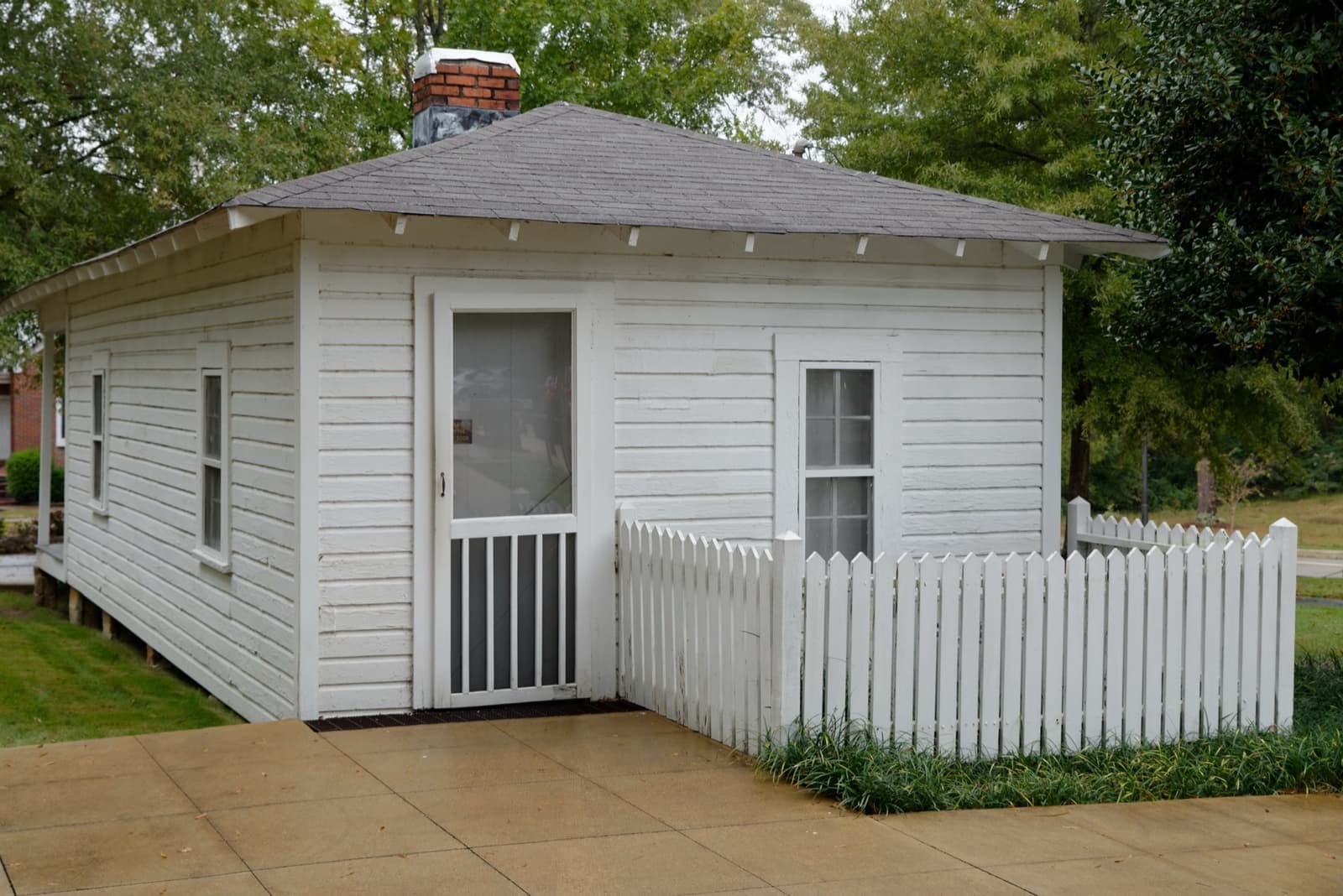 A small white two-room wooden house with a porch