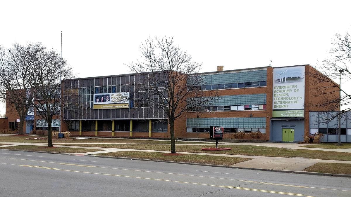 A long low brick high school building behind a lawn on a grey winter day