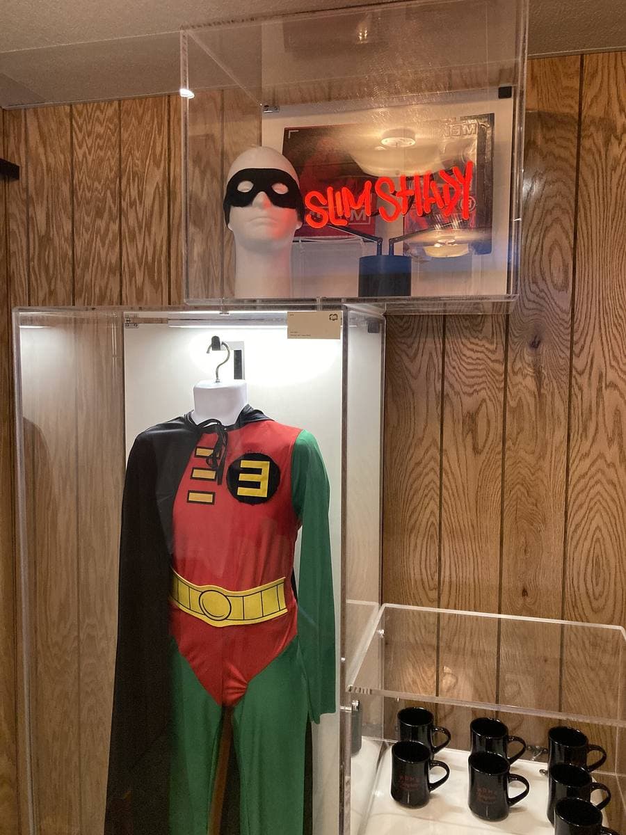 A green, red and yellow superhero costume displayed in a glass case