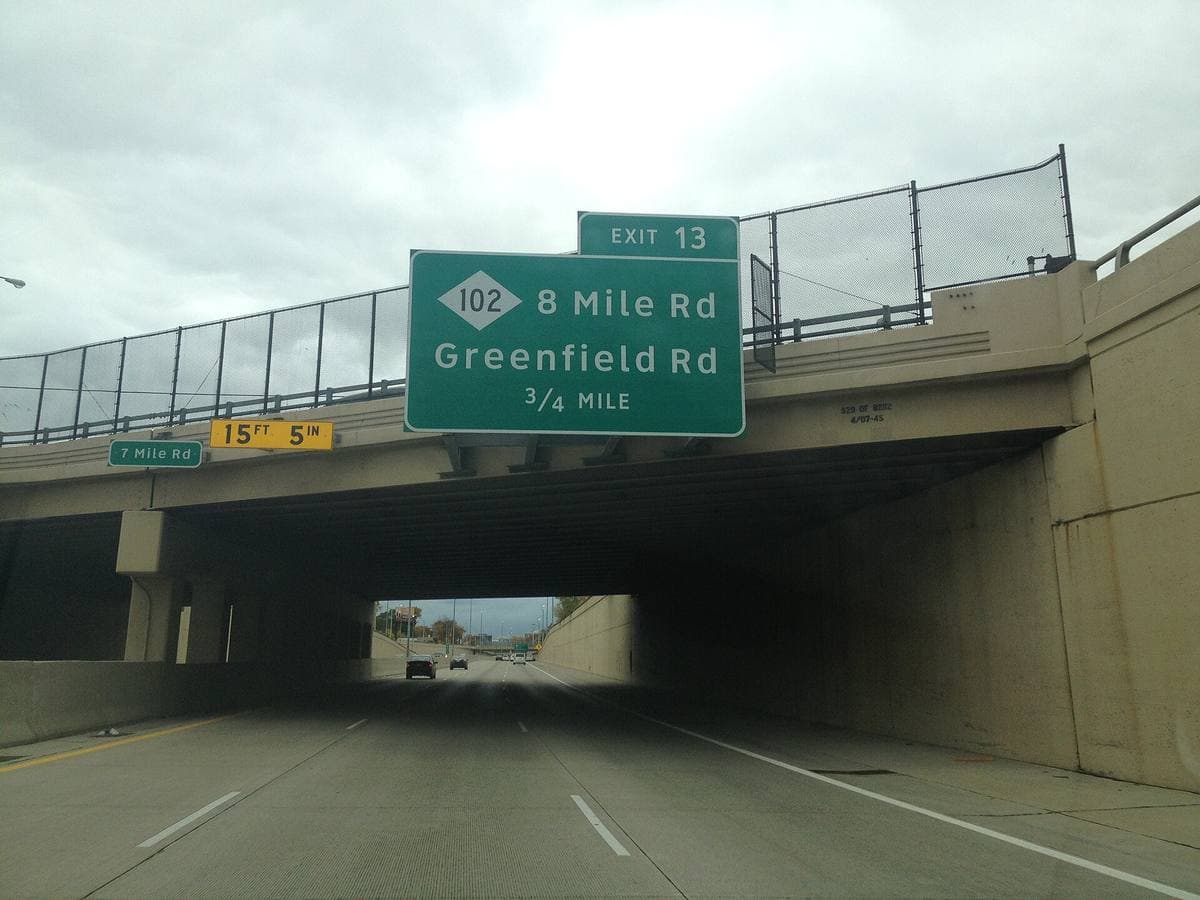 A concrete road bridge marked 7 Mile Road crossing above a freeway