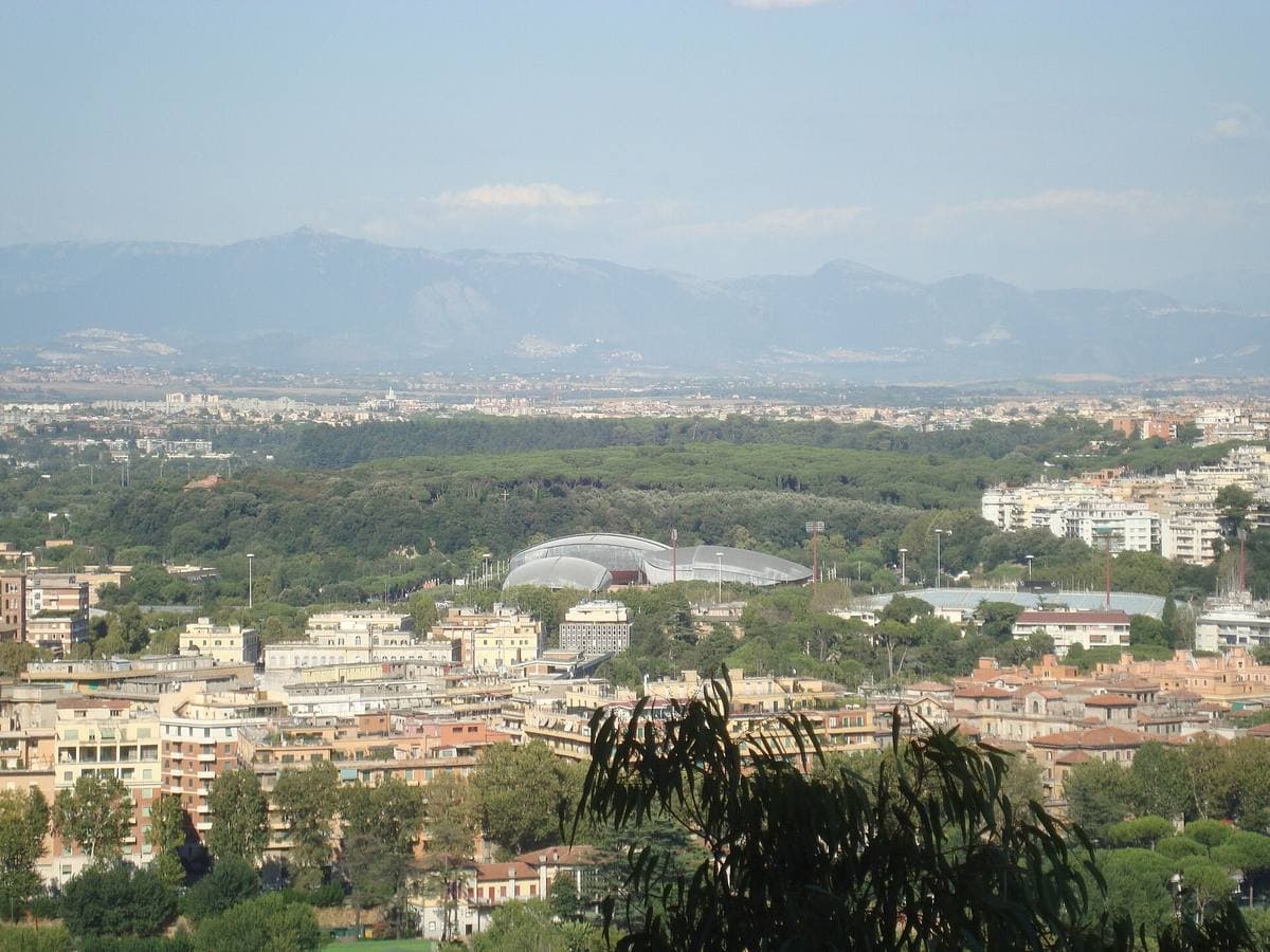 A wide view over Rome with the grey shells of the Auditorium halls among trees