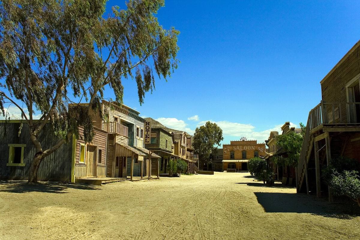 A western street of wooden buildings and a saloon under eucalyptus trees