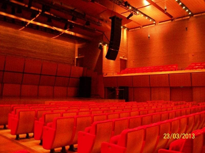 A concert hall with rows of red seats and warm wooden walls
