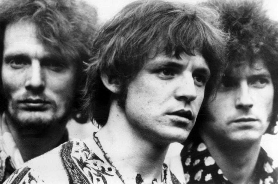 Close black-and-white portrait of the three members of Cream, faces overlapping, Eric Clapton on the right