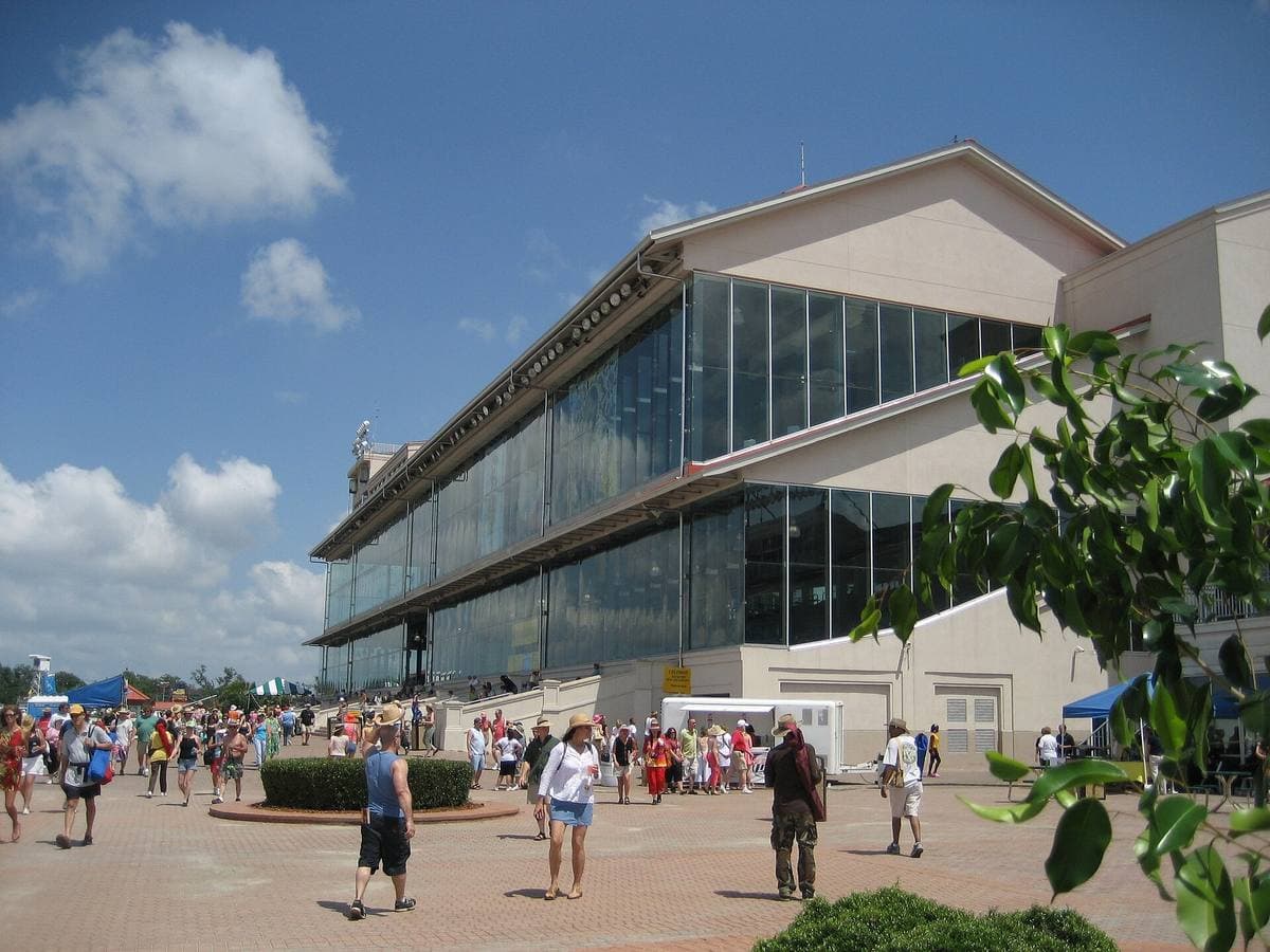 Festival crowds outside a glass-fronted racecourse grandstand