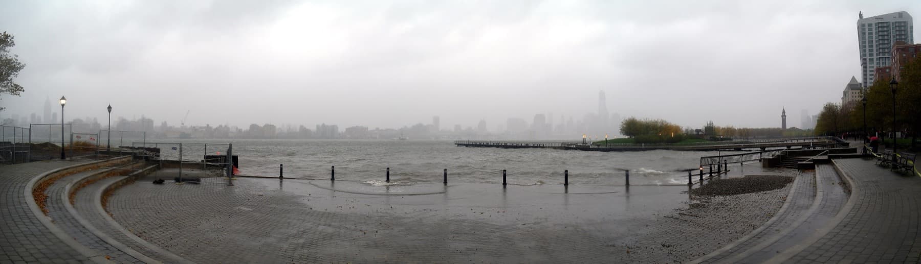 A riverside amphitheatre lawn with the Manhattan skyline across the water