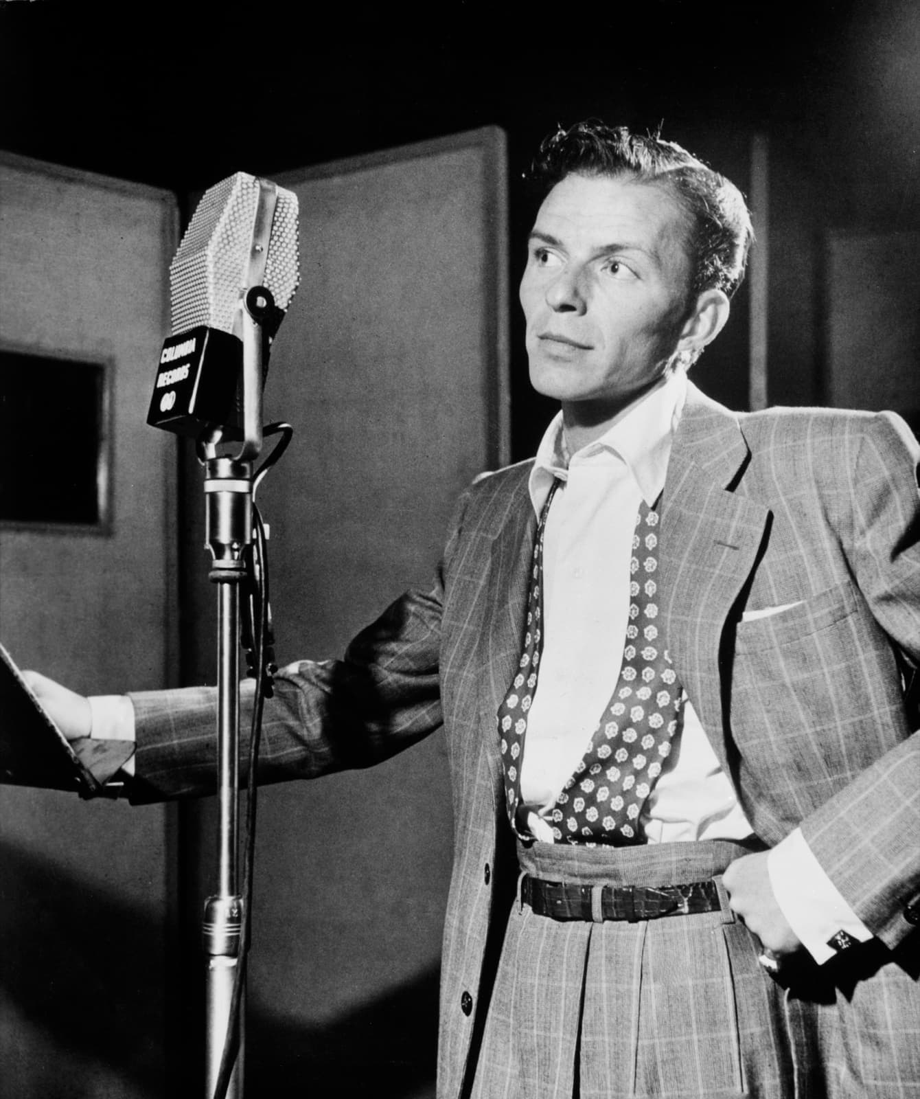 Frank Sinatra at a studio microphone in a checked jacket and bow tie