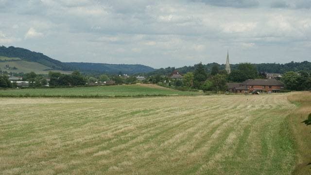 Fields and trees with a town spire and a hill beyond