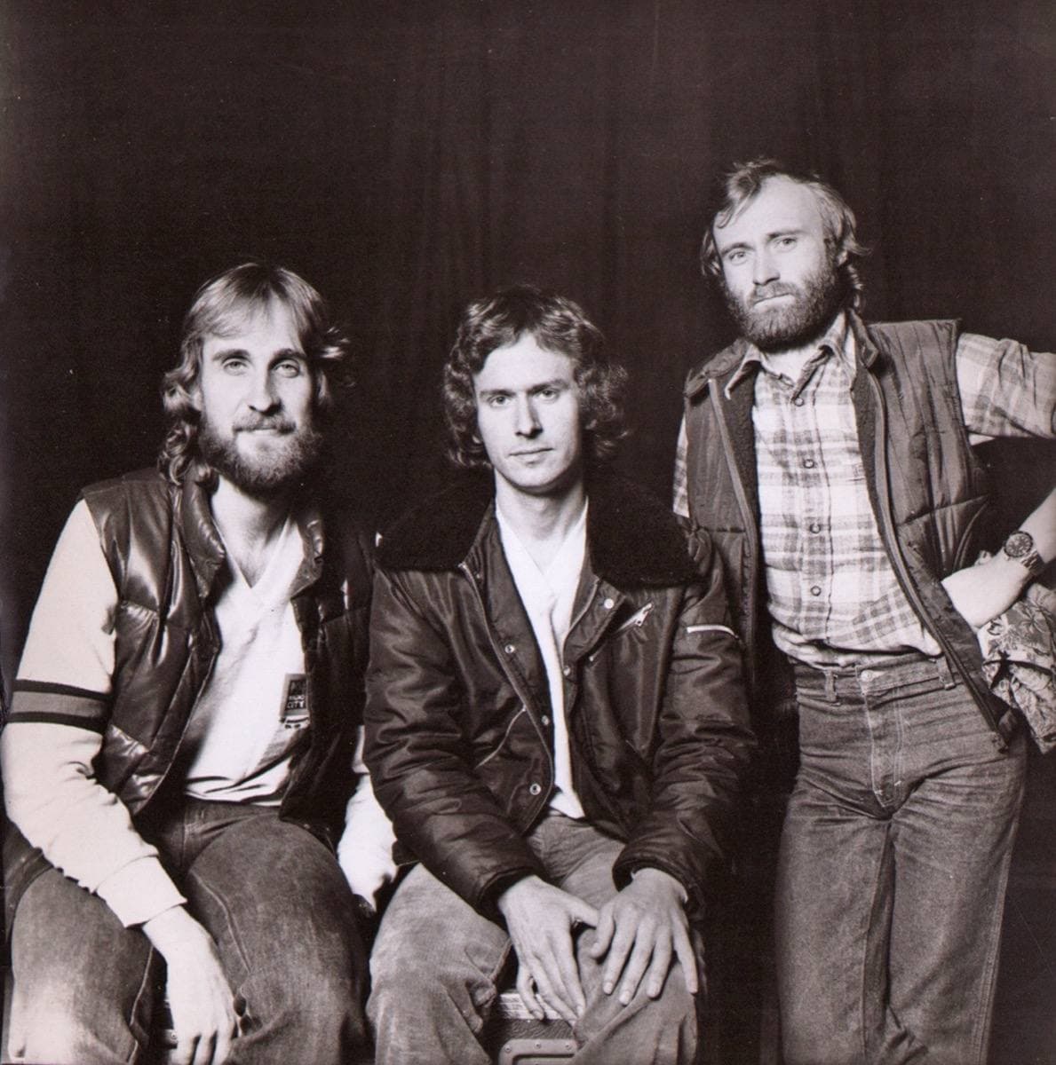 Three men sitting and standing in a studio portrait, in jeans and jackets