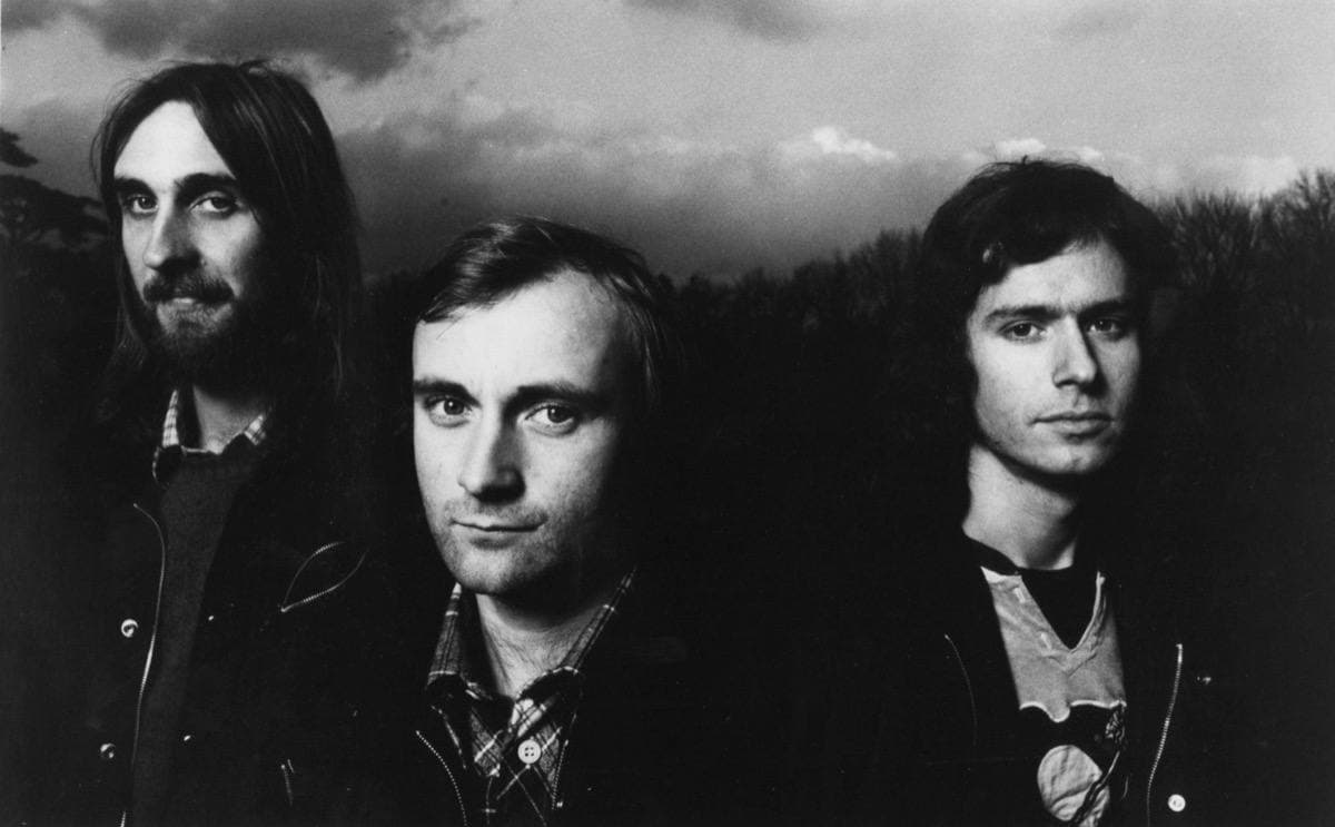 Three men in front of dark trees under a cloudy sky