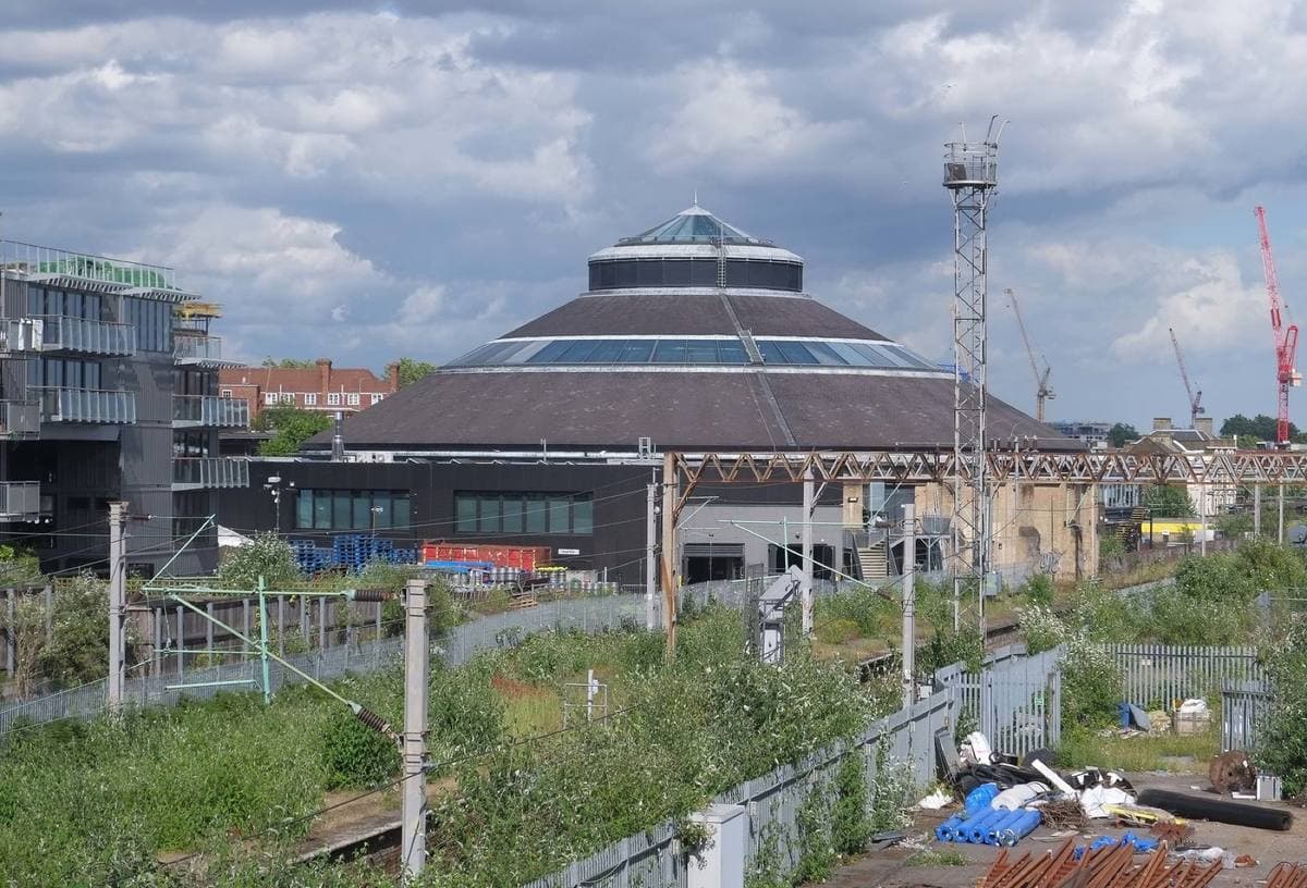 The round brick engine shed of the Roundhouse with its low conical roof, seen over railway land
