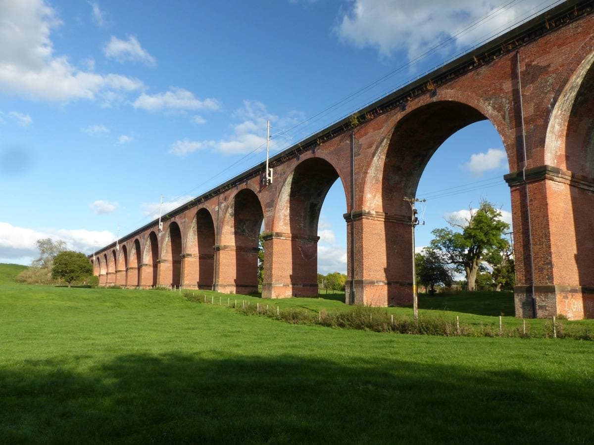 A tall brick railway viaduct over a valley near Holmes Chapel