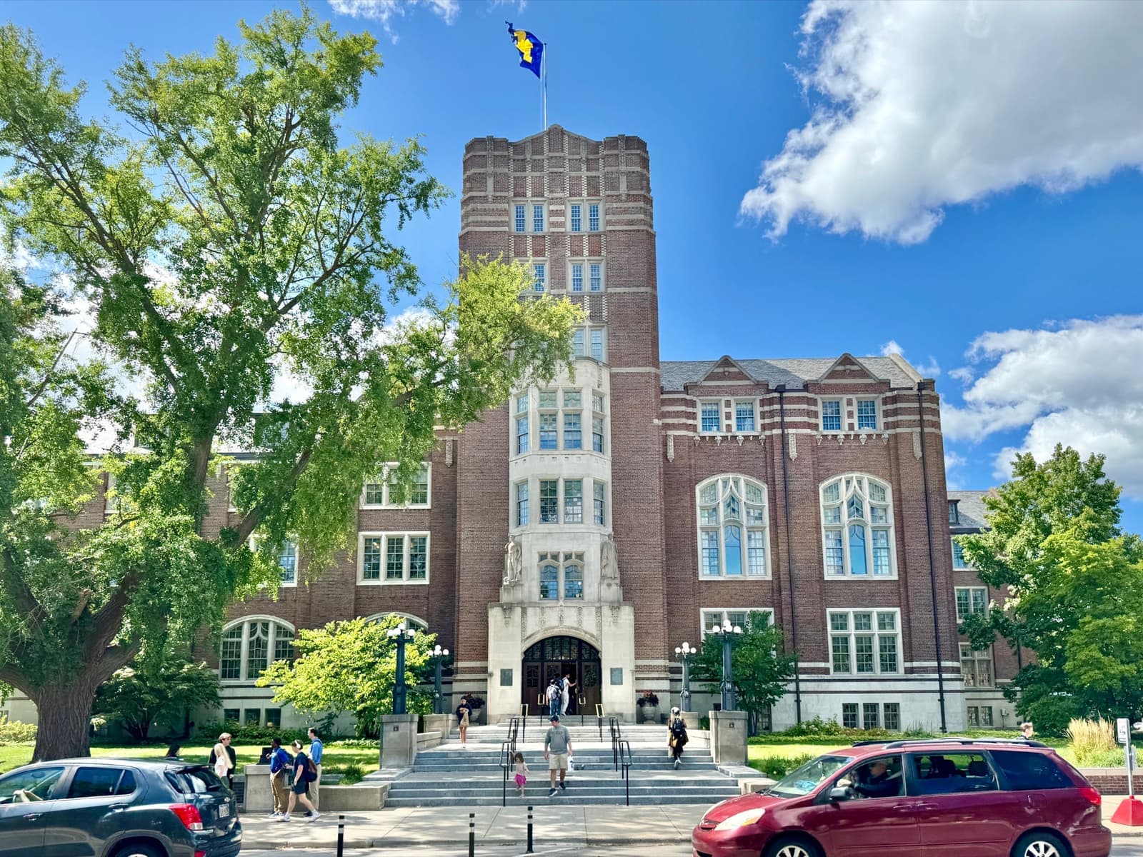 The tall Gothic brick front of the Michigan Union framed by green trees