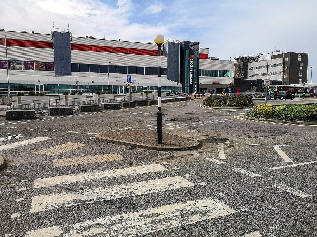 An airport terminal forecourt with a zebra crossing