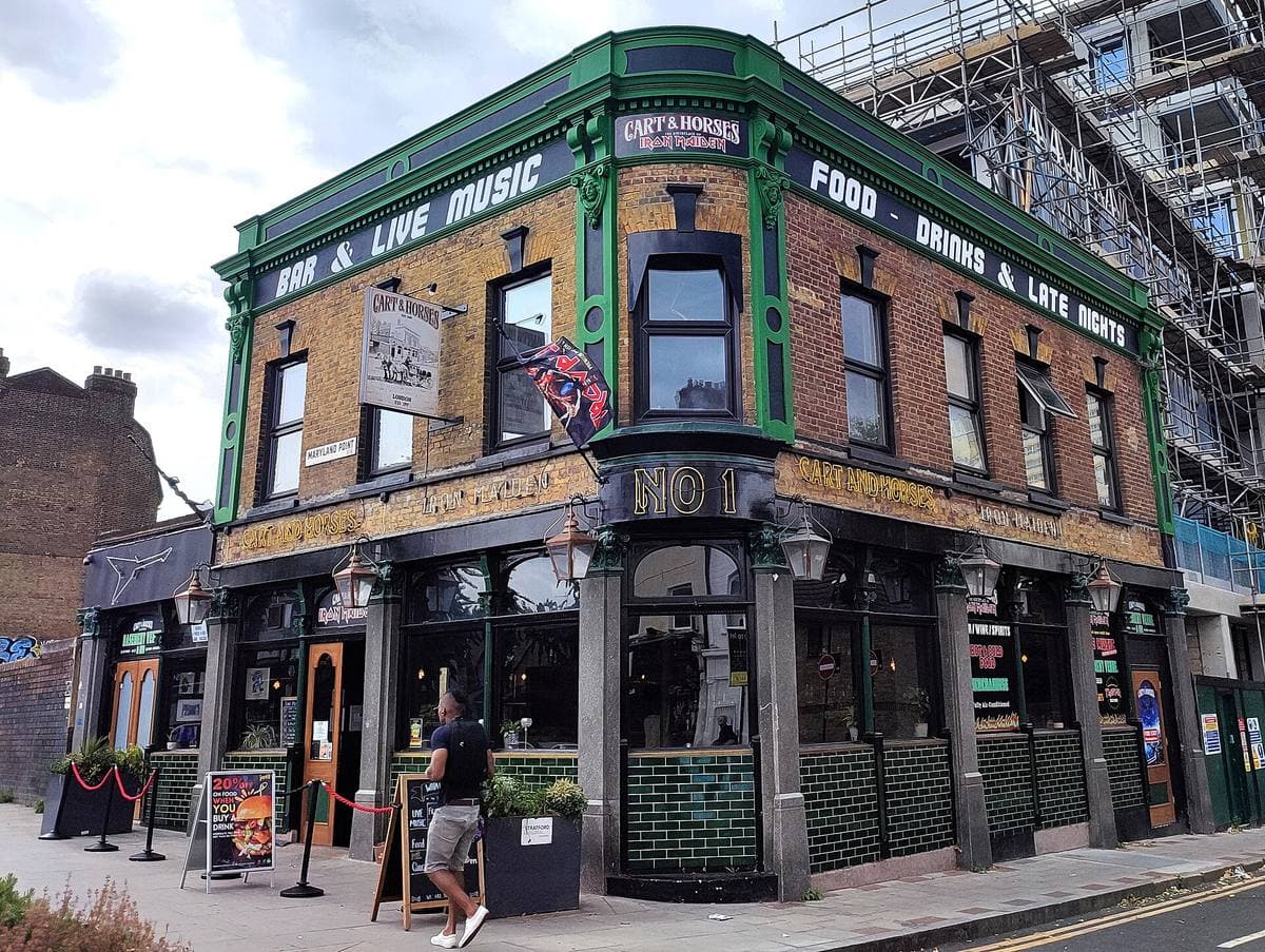 A green-tiled corner pub with gold signwriting