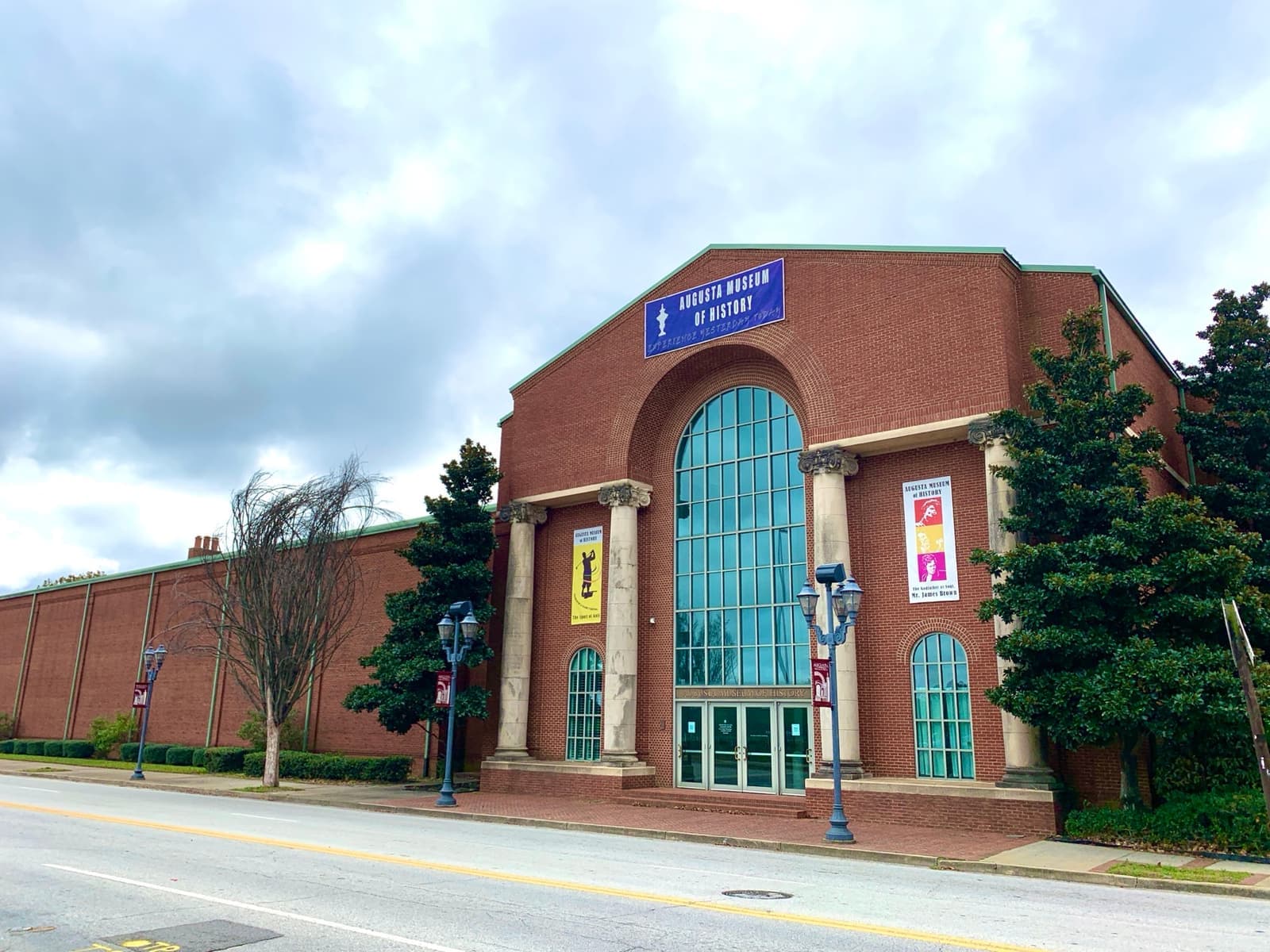 A red-brick museum building with a tall arched glass entrance