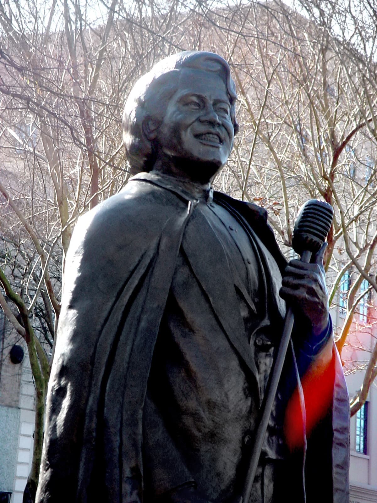 A life-size bronze of James Brown holding a microphone stand, in a long coat