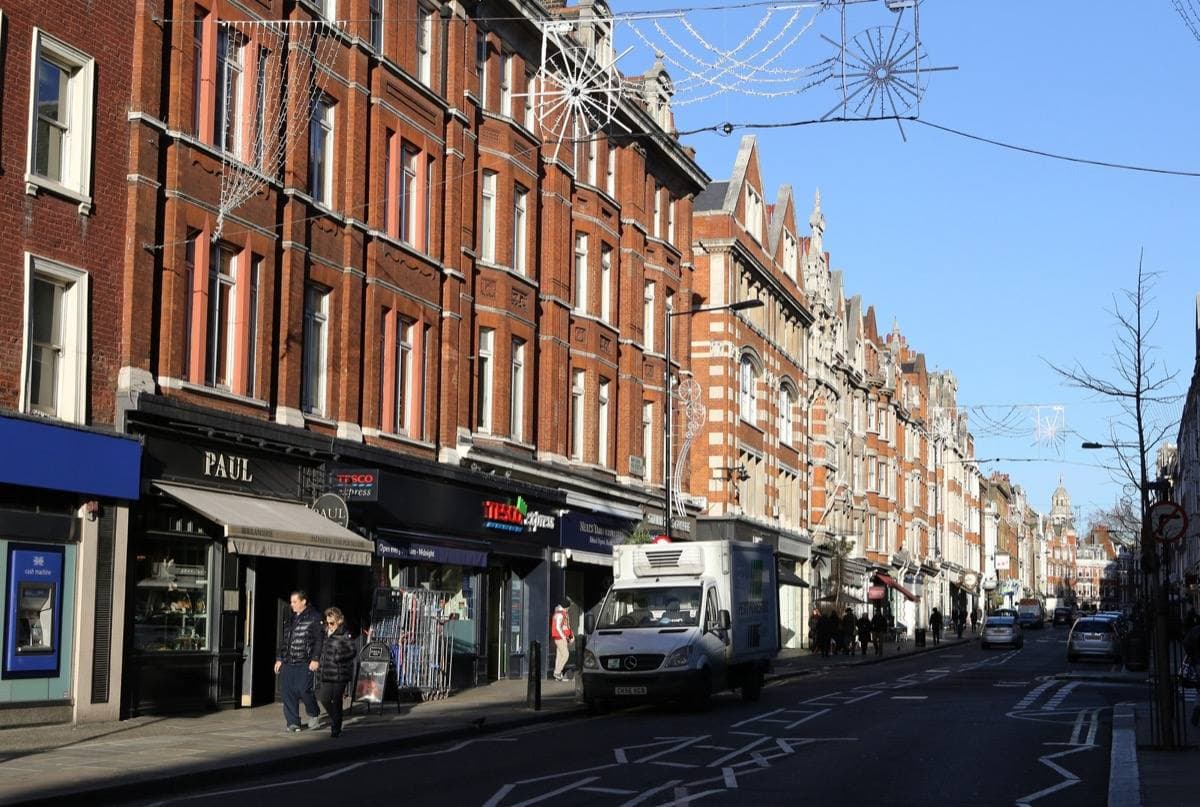 A London high street of red-brick mansion blocks and shop fronts