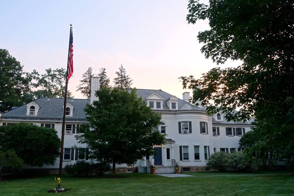 A white clapboard building with a porch behind a lawn