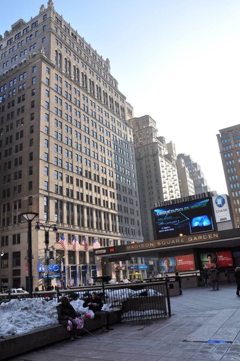 The curved entrance of Madison Square Garden beside a tall office building