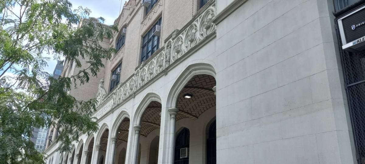 A pale brick school building with arched ground-floor windows and lettering