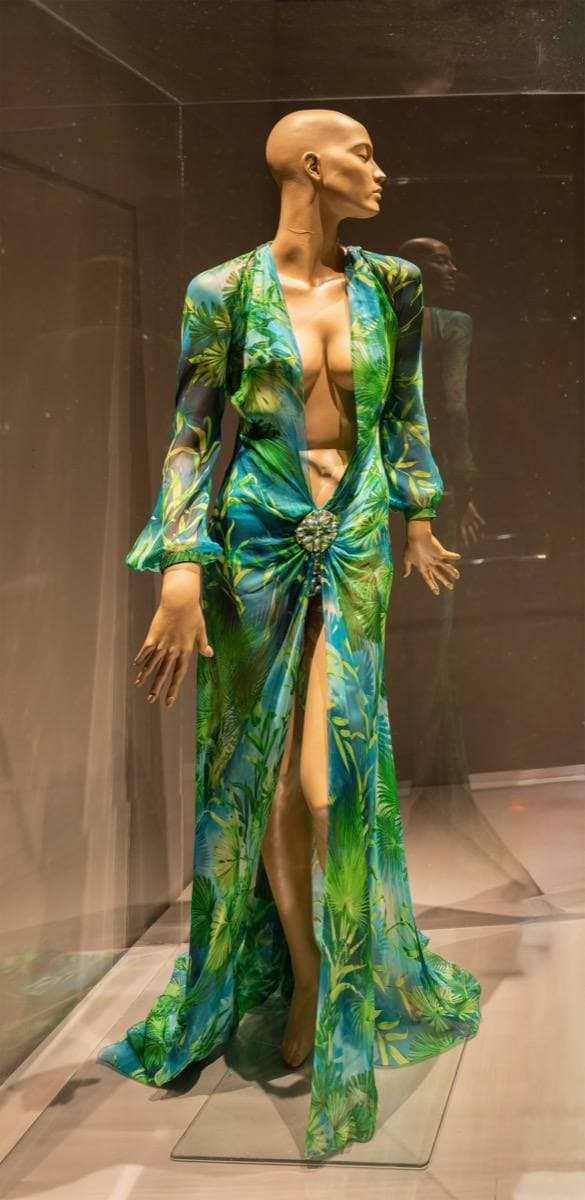 A green leaf-print silk chiffon dress on a mannequin in a museum case