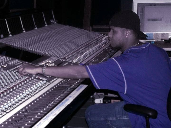 A recording engineer at a large mixing desk in a studio control room
