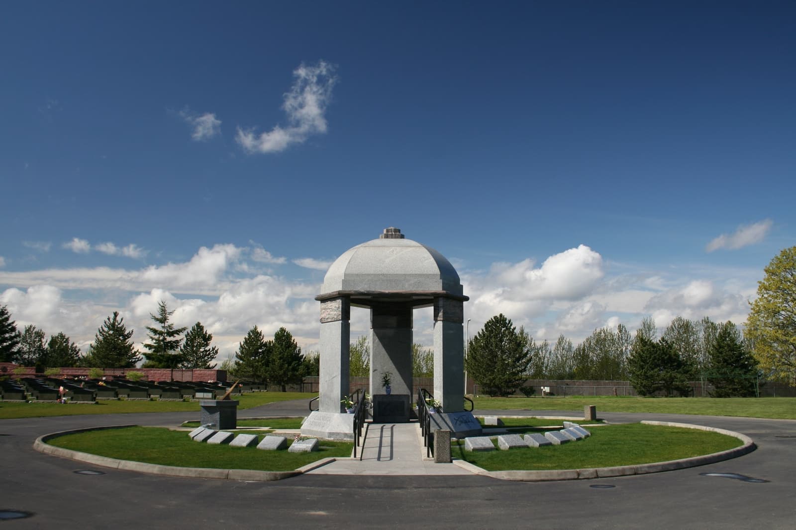A granite dome on three columns over a stone, on a lawn