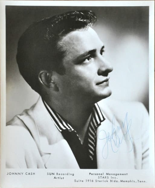 A young Johnny Cash with a guitar, in a studio portrait