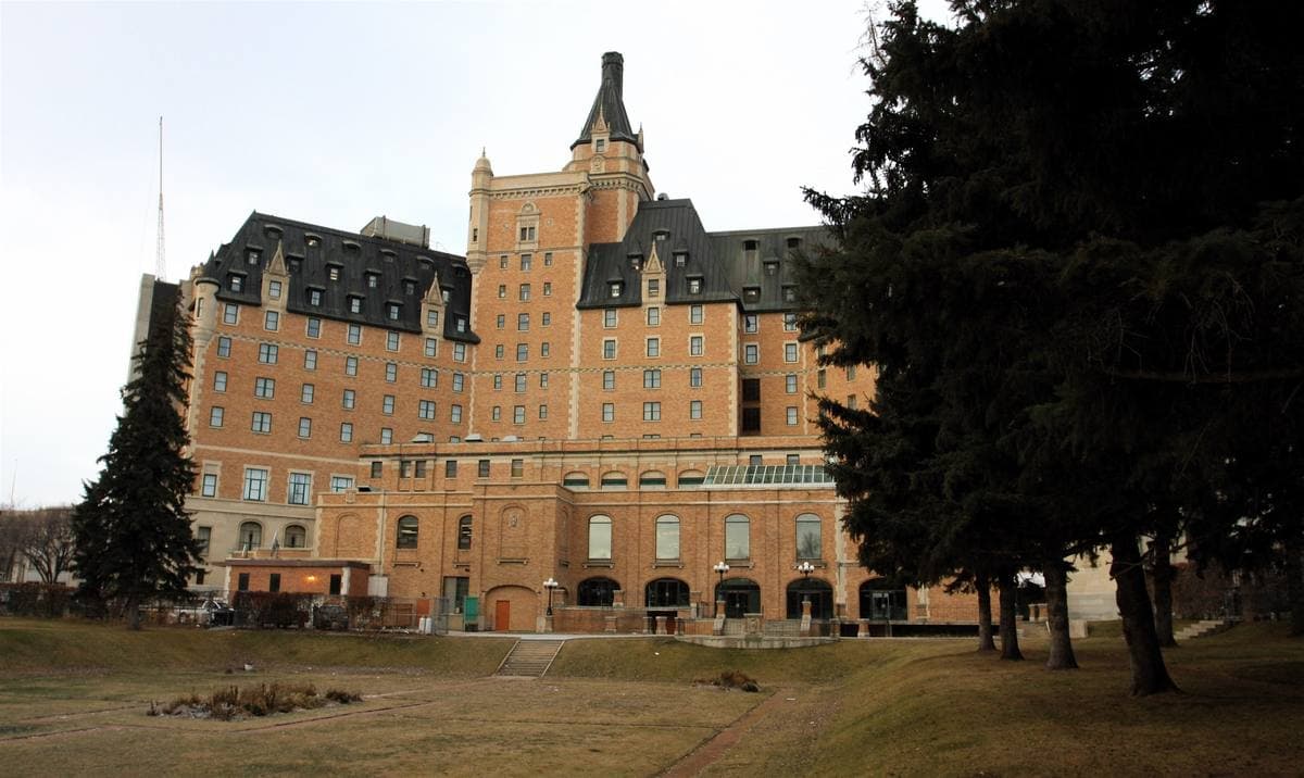 A tall château-style hotel with a copper roof and turrets above a river