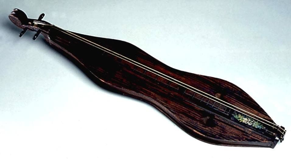 A long, narrow hourglass-shaped wooden dulcimer with heart-shaped sound holes