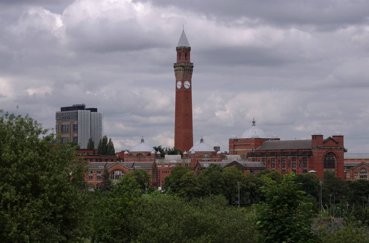 Red-brick university buildings and a clock tower across a lawn