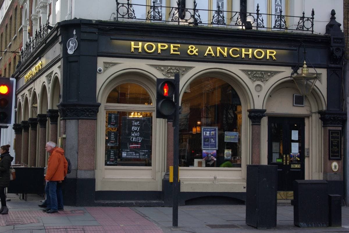 A corner pub with a painted sign and lit windows on Upper Street