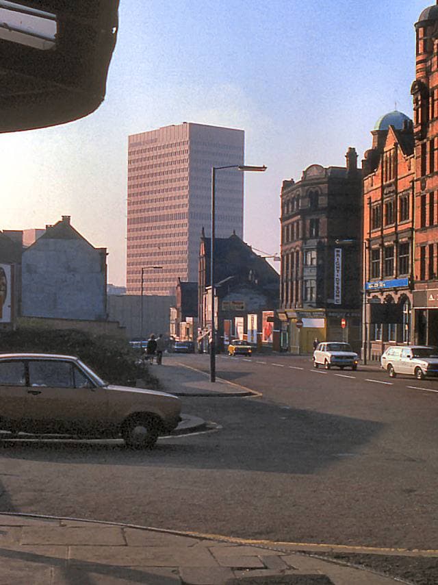 A grey Manchester street in 1978 with old buildings and a bus