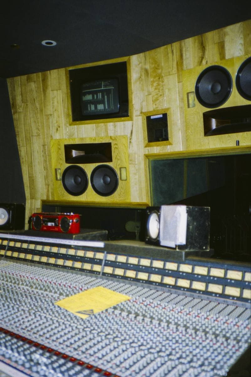 A recording studio control room with a large mixing desk