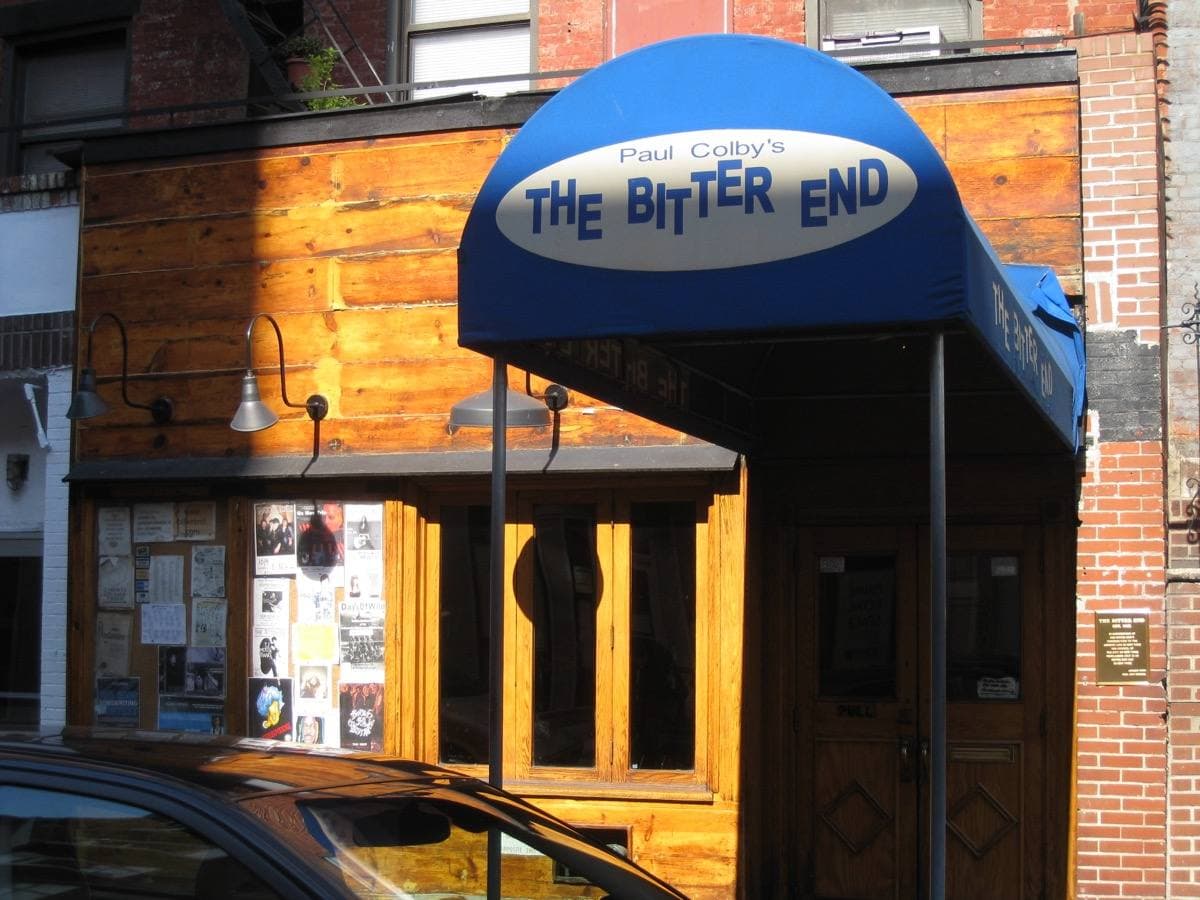 A blue canopy reading The Bitter End over a wooden-fronted club