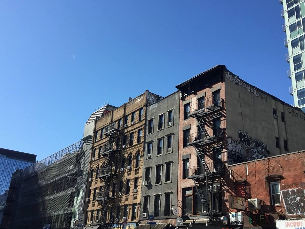 Old tenement fronts with fire escapes on a Lower East Side block