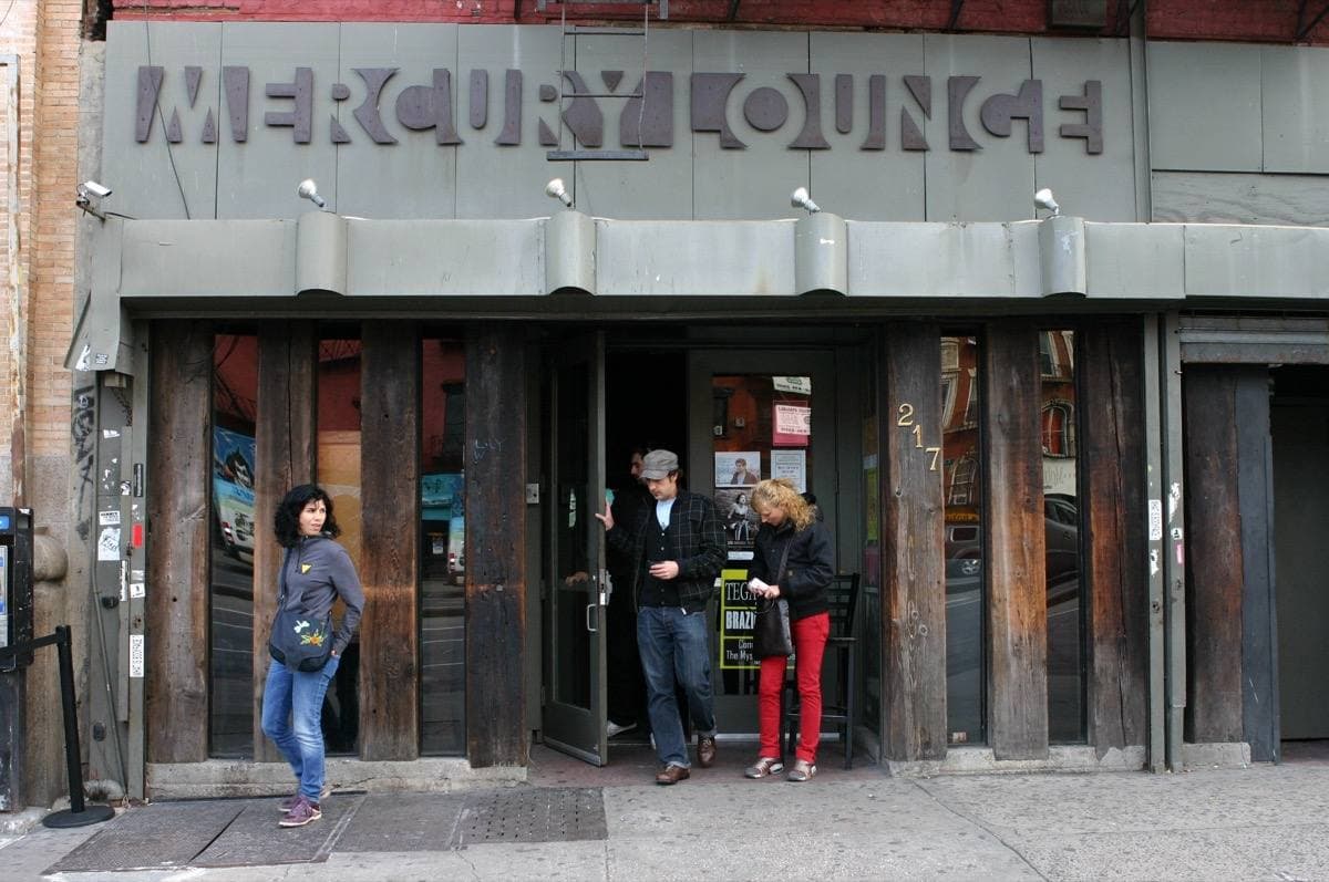 A dark club front with MERCURY LOUNGE lettered above the door