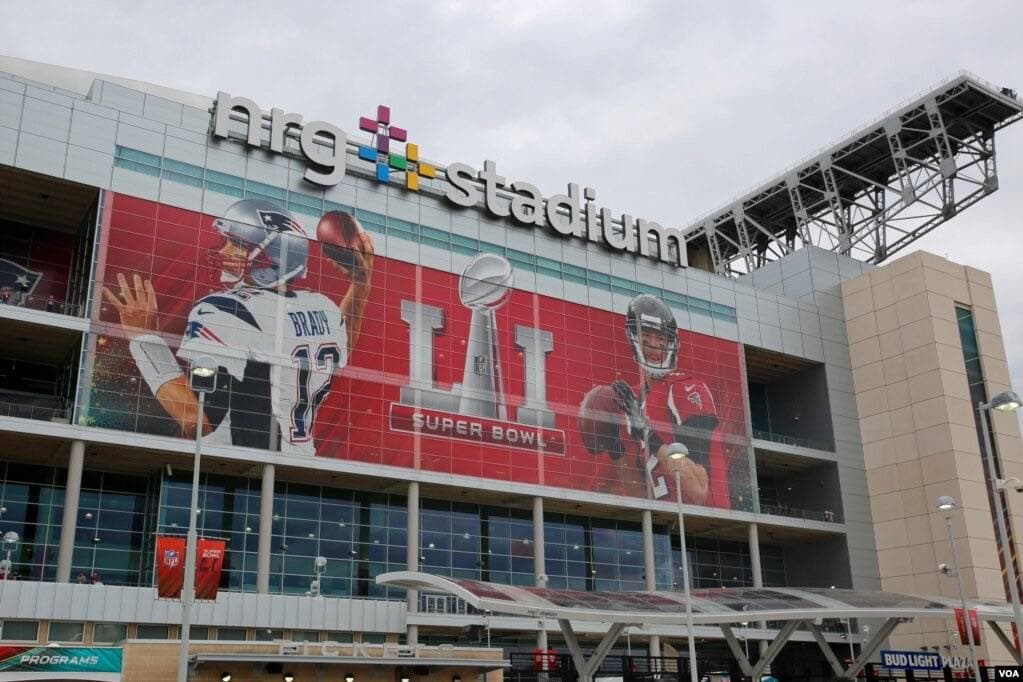 The outside of a large stadium hung with a Super Bowl banner