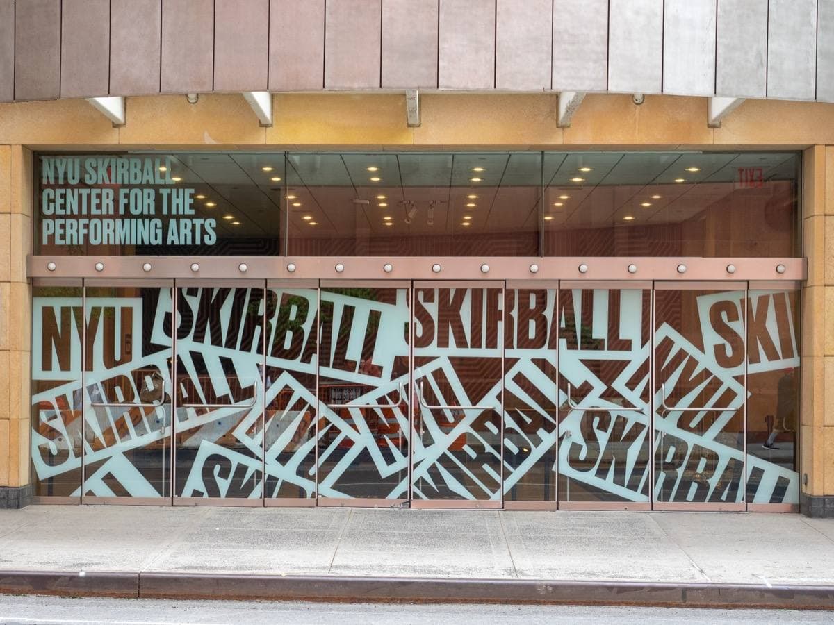 A glass entrance lettered NYU Skirball Center for the Performing Arts