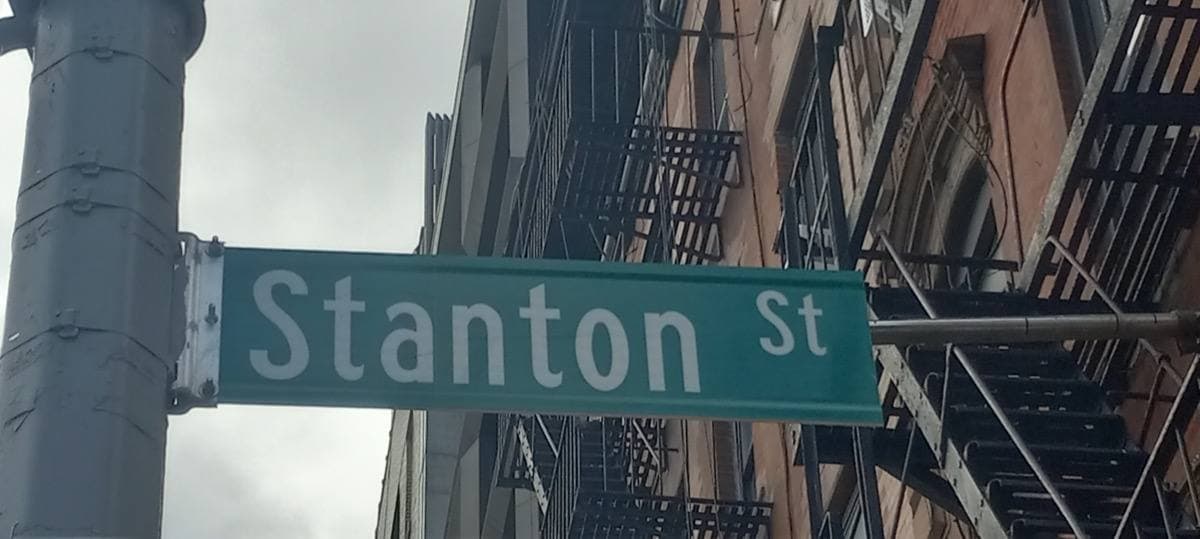 A green street sign reading Stanton St