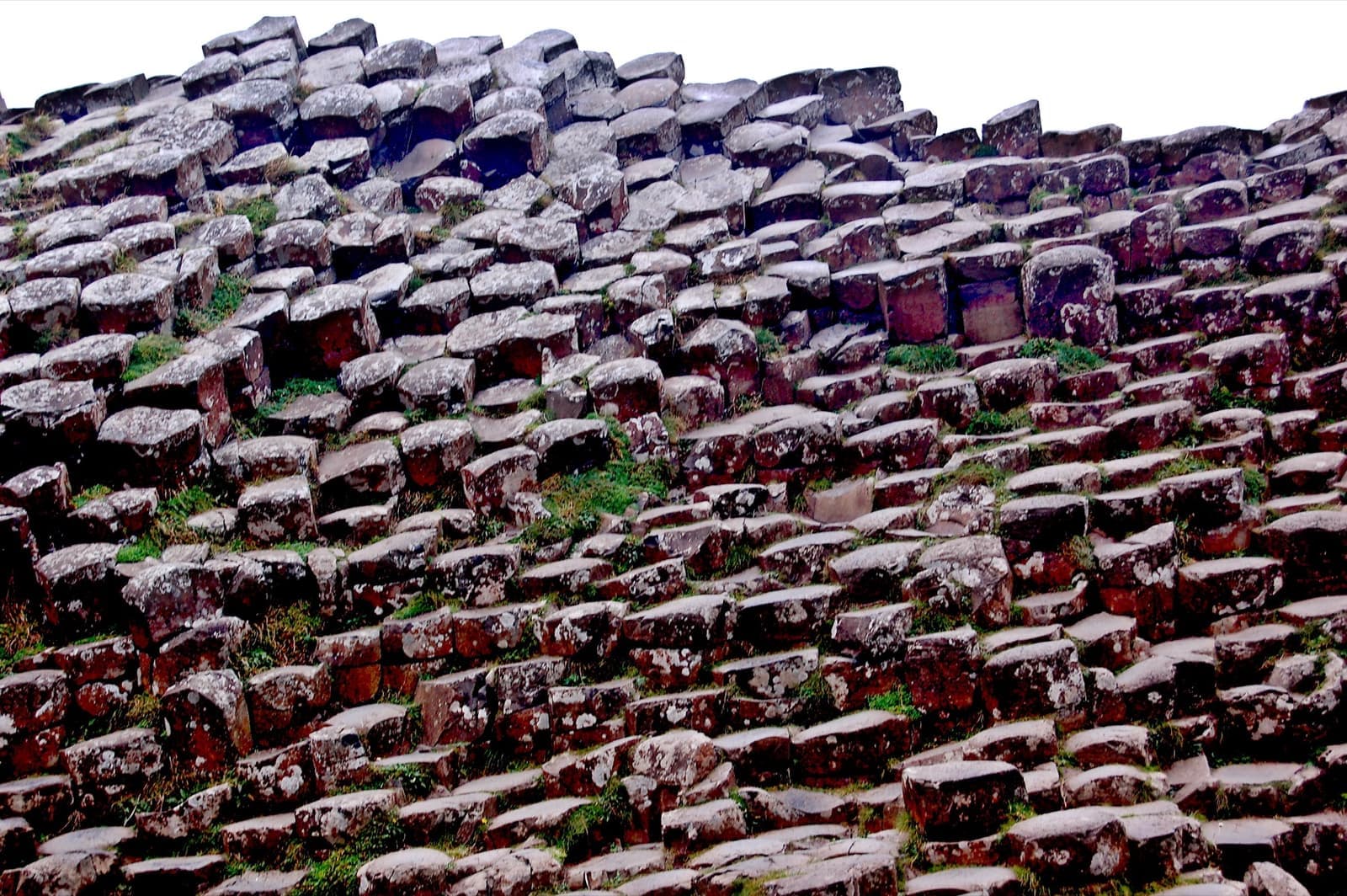 Stepped hexagonal basalt columns running down into the sea under a grey sky