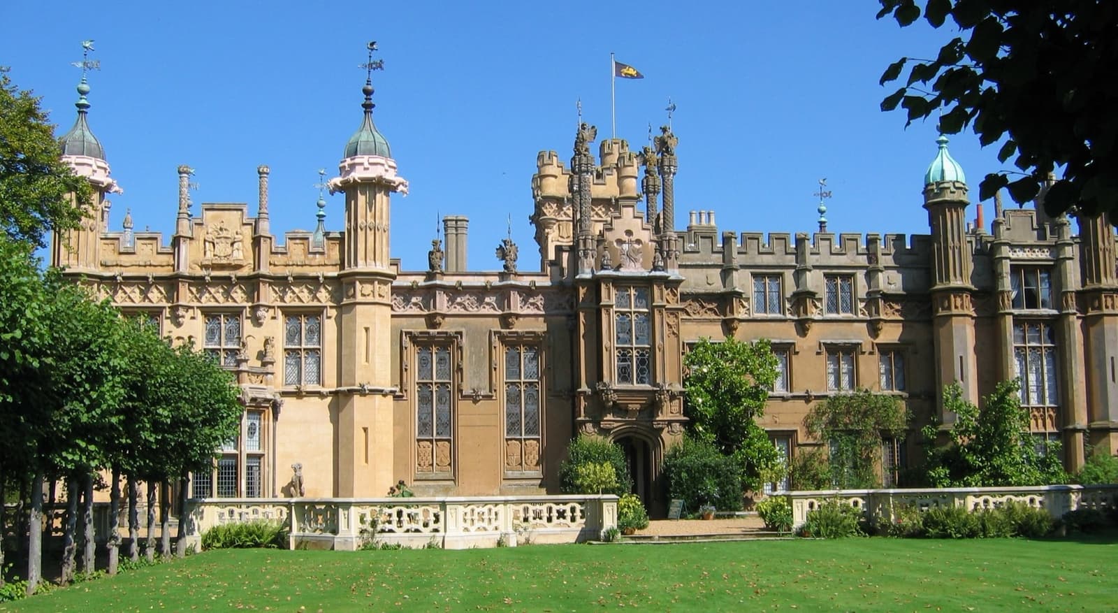 The turreted Gothic front of Knebworth House across a lawn
