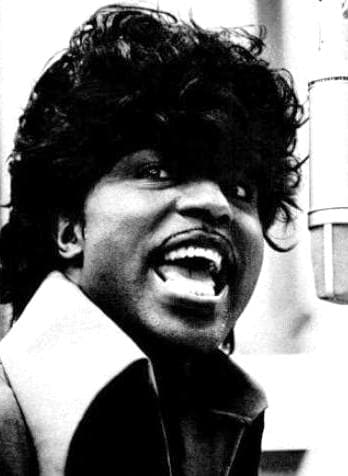 Little Richard singing at a microphone with his mouth open
