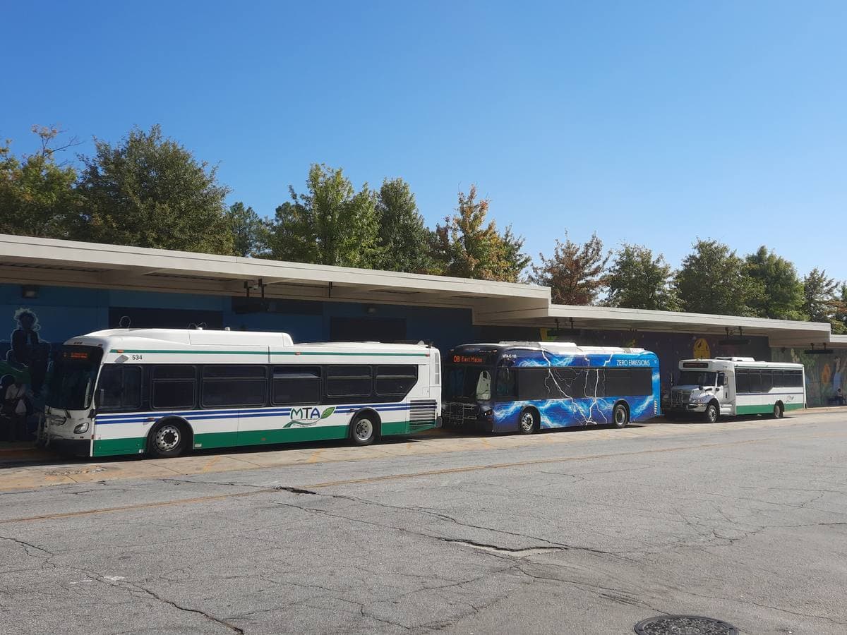 Three city buses parked at a covered bus bay