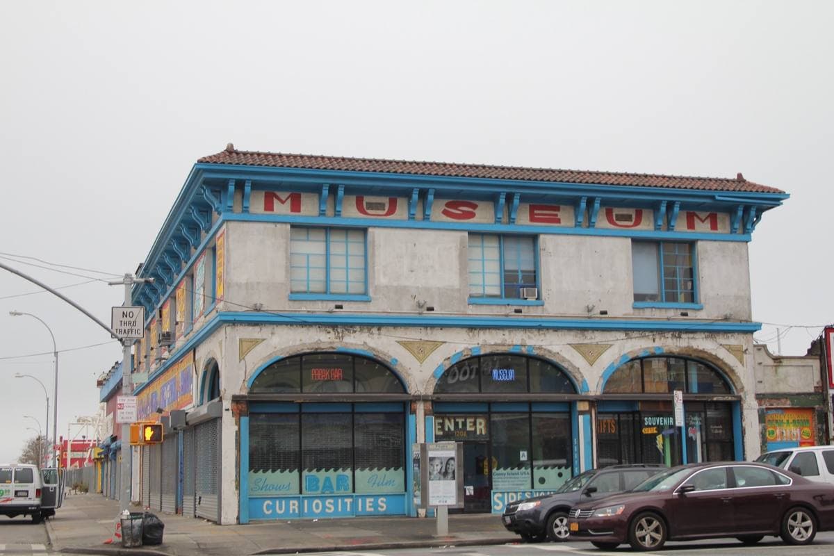 A cream and turquoise 1917 building with a painted MUSEUM sign and a row of arched windows