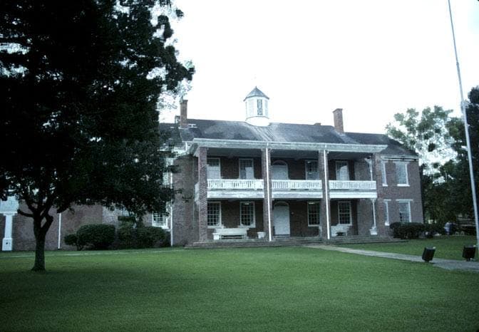 A white courthouse with columns under trees