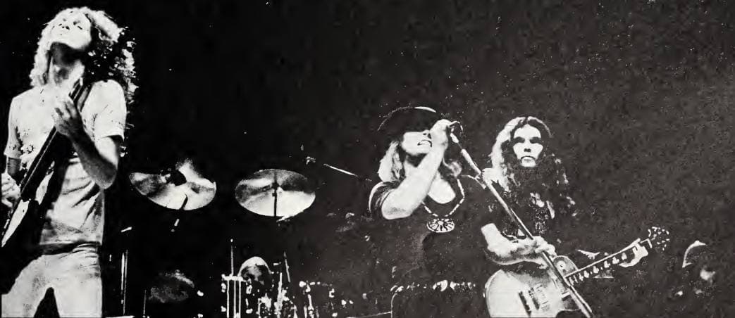 Three young men with long hair, two of them holding guitars